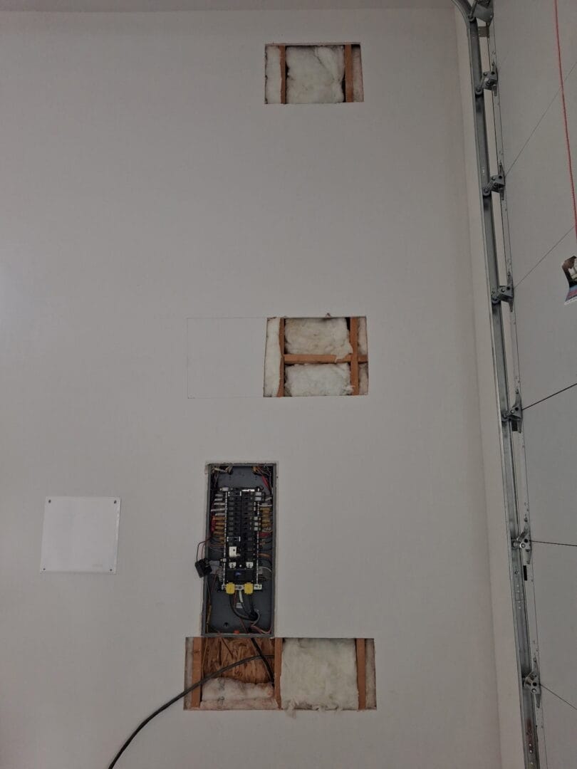 Garage wall with fuse box before drywall repair